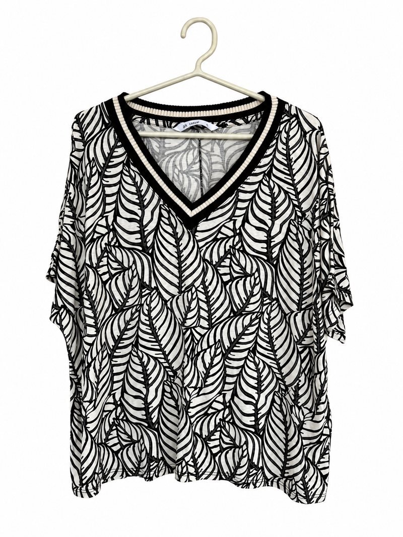 Frente da blusinha branca com folhas pretas e decote em V